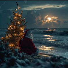 a santa claus sitting on the beach next to a christmas tree with lights in it