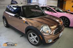 two cars are parked in a garage with pink and gold paint on the hoods