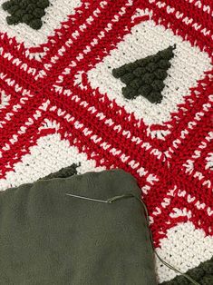 a red and white afghan with a green bag on the ground next to it's side