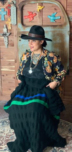 a woman sitting on the ground wearing a black hat and dress with multicolored stripes