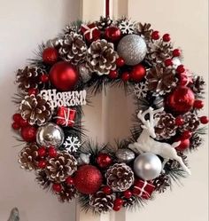 a christmas wreath hanging on the front door with ornaments around it and reindeer ornament