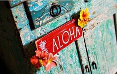 a sign that says aloha hanging from the side of an old wooden door