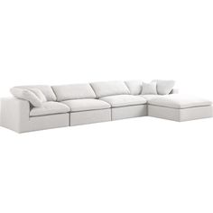 a white sectional couch with pillows on it's back and side facing the sofa