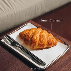 a croissant sitting on top of a white plate next to a fork and knife