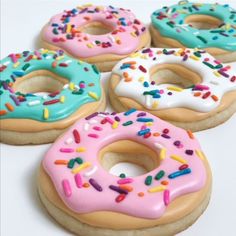 four donuts with frosting and sprinkles are on a white surface