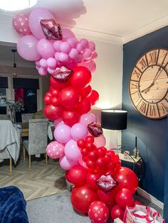 there is a large number of balloons on the floor in this living room with a clock behind it