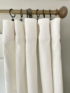 four white curtains hanging from a wooden rod