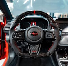 the interior of a car with red and black leather trims, steering wheel and dashboard