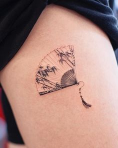 a woman's thigh with a fan tattoo on it