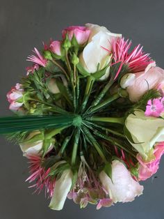 pink and white flowers are arranged in a circular arrangement on a gray surface with green stems