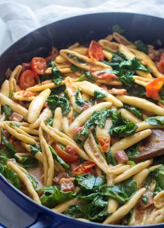 a pan filled with pasta and spinach covered in sauce