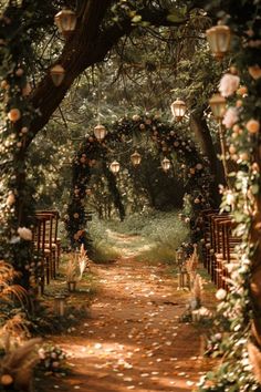 an outdoor wedding ceremony with lanterns and flowers on the path leading to the aisle that leads into the forest