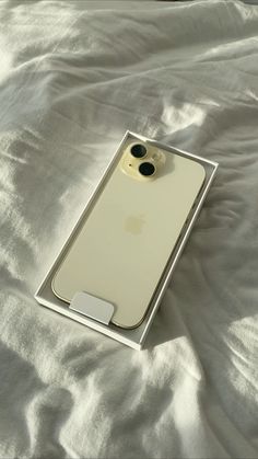 an iphone case sitting on top of a white sheet covered bed next to a cell phone