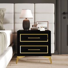 a night stand with two drawers and a lamp next to it on a white bed