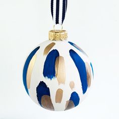 a blue and white ornament hanging from a string on a white background with gold accents