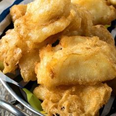 some fried food is in a bowl on a table with a striped napkin and fork