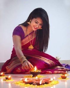 a woman sitting on the ground with candles