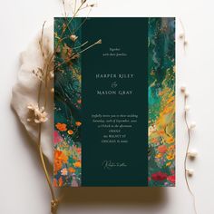 an elegant wedding card with flowers and greenery on the front, in dark green