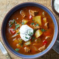 a bowl of soup with meat, potatoes and sour cream