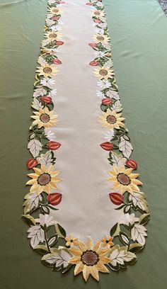 a long table runner with sunflowers and leaves on green fabric, ready to be used as an applique