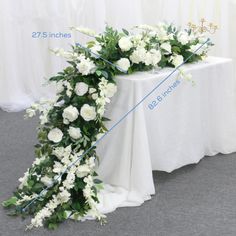 a table with white flowers and greenery on it