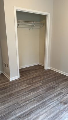 an empty room with wood flooring and white closet doors on either side of the door