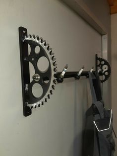 there is a clock on the wall with gears hanging from it's back end