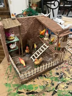 a toy house made out of clay with chickens and other things on the table next to it