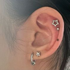 an ear with three stars on it and two piercings attached to the side of the ear