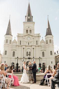 a bride and groom are standing in front of a church with their wedding ceremony guests