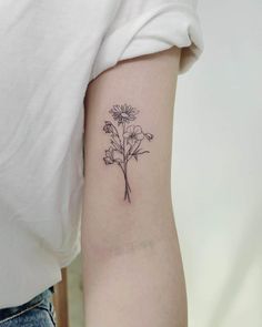 a woman's arm with a small flower tattoo on the back of her left arm