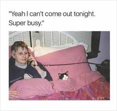 a woman laying in bed with a cat on her lap while talking on the phone