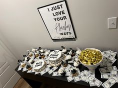 a table topped with lots of cupcakes and cake next to a bowl of money