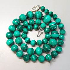 On offer is this high quality Vintage natural emerald green Malachite graduated bead necklace. This beautiful vintage necklace consists of genuine rich emerald blue green round beads that is hand-knotted with silk cord and finished with a sterling silver gold filigree clasp with a safety latch that opens and closes tightly. These Malachite gems are highly polished and very lustrous. The glossy Malachite beads range in size from 1/2 inch diameter at the front to 6/16 inch diameter at the clasp. T Malachite Gemstone Bead Necklaces, Malachite Gemstone Beads Necklace, Turquoise Round Beads Emerald Necklace, Vintage Green Oval Beads Jewelry, Vintage Green Oval Beaded Jewelry, Vintage Green Beaded Necklaces With Oval Beads, Vintage Green Beaded Necklace With Oval Beads, Vintage Green Oval Bead Necklaces, Vintage Green Oval Beaded Necklaces