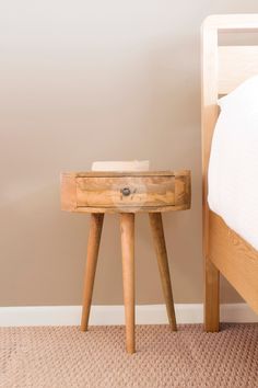 a small wooden table sitting next to a bed