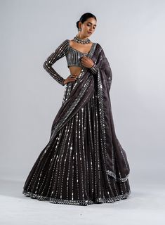 Editor's Note Featuring a charcoal grey real hand cut mirror heavily embellished lehenga paired with a mirror work full sleeve blouse and dupatta Fabric: Lehenga: georgette, blouse: georgette, dupatta: satin organza Color: Charcoal grey Component: Lehenga, blouse and dupatta Sleeve type: Full Occasion: Sangeet Care: Dry Clean Only About the Designer Vvani by Vani Vats- an Indian ethnic women’s wear label. It is a depiction of the royal and intricate handcrafted embroideries in unconventional des Grey Lehenga, Vani Vats, Mirror Work Lehenga, Lehenga Dupatta, Mirror Work Blouse, Black Lehenga, Full Sleeve Blouse, Grey Mirror, Georgette Dupatta