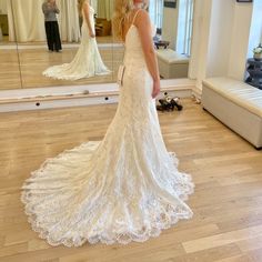 a woman standing in front of a mirror wearing a wedding dress with an open back