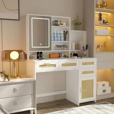 a white desk topped with a mirror next to a lamp and drawers in a room