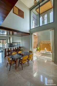 a dining room table with yellow chairs in front of an open floor plan and large windows