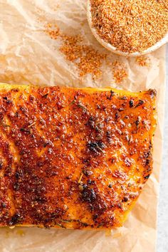 grilled salmon on parchment paper with seasoning next to it and a bowl of spices