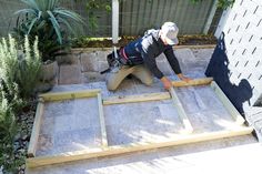 a man working on the side of a house with wooden boards in front of him