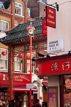 people are walking down the street in front of chinese restaurants and stores on a sunny day