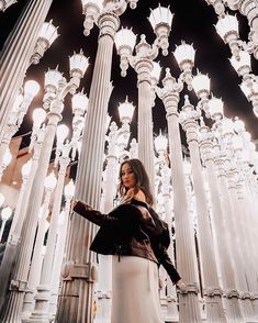 a woman is standing in front of columns and chandeliers with her arms outstretched