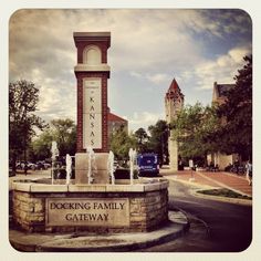 a clock tower in the middle of a park with water spouting from it