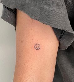 a person with a smiley face tattoo on their arm