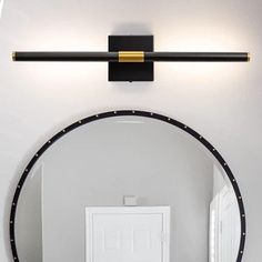 a round mirror mounted to the side of a wall next to a white door in a bathroom