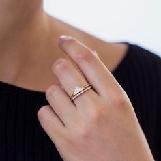 a woman's hand wearing a gold ring with two diamonds on it and a black shirt