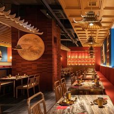 a restaurant with wooden tables and chairs, red walls and wood paneled ceilinging