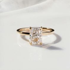 an engagement ring with a princess cut diamond in the center, on a white background