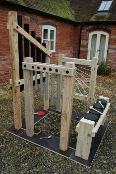 a wooden playground set sitting in front of a brick building with stairs and railings